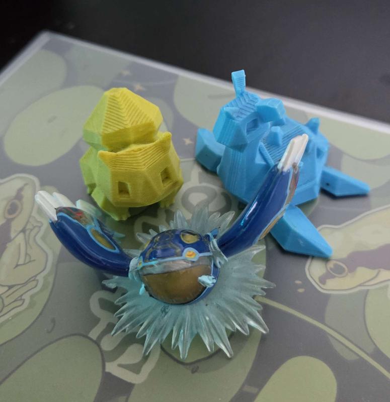 A photograph of Jeydis’s special Pokémon items! They include 3D printed Bulbasaur and Lapras figures and a Kyogre figure from a close friend